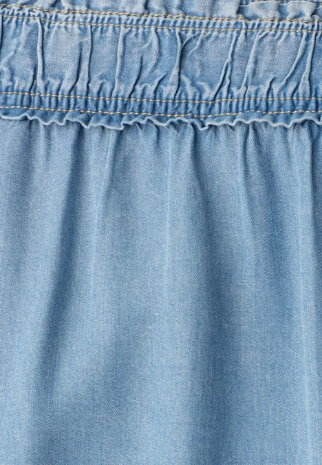 Nahaufnahme von hellblauem Denimstoff mit elastischem, gerafftem Bund.